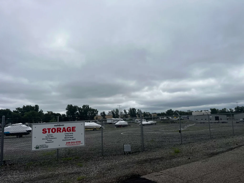 Secure fenced outdoor storage yard at North Oakland Storage near White Lake, MI, with boats and trailers parked inside